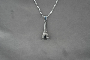 Detailed macro view of silver Eiffel Tower pendant on stainless steel box chain