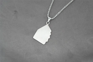 Detail of silver box chain with artistic multiple face silhouette pendant on fabric