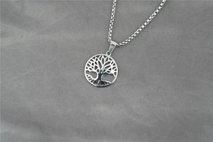 Detailed view of silver tree of life cutout pendant on a delicate box chain necklace