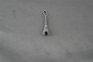 Macro shot of silver Eiffel Tower pendant with ALICE engraving and grid textures