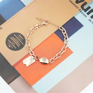Minimalist rose gold titanium steel bracelet with Good Luck tag on fashion magazine