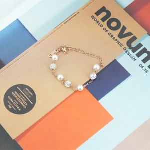 Bracelet en or rose avec perles et boules serties de diamants sur une revue chic