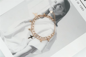Detail of rose gold double-layer bracelet featuring cross charms and polished steel beads