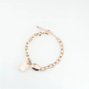 Rose gold chain bracelet with Good Luck charm and oval bead on white background