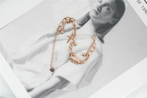 Detail of rose gold layered bracelet featuring cross charms, beads and heart pendant