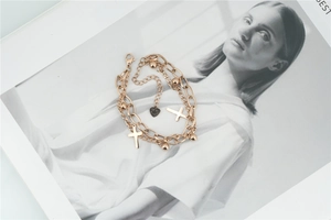 Detail of rose gold double-layer cross bracelet with steel beads on magazine background