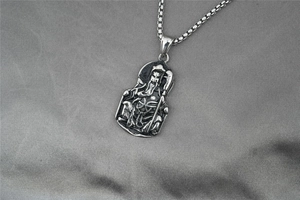 Dettaglio del ciondolo Guan Yu in stile vintage con incisioni dell'armatura in acciaio
