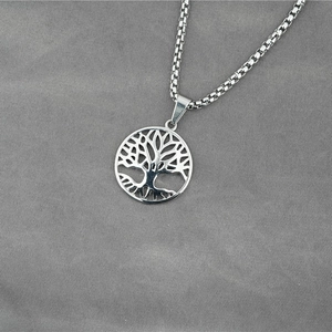 Polished stainless steel Tree of Life pendant necklace with box chain on grey fabric