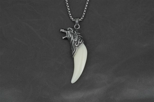 Detailed shot of vintage silver wolf head pendant with ivory-white resin tusk on box chain