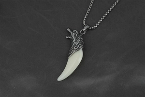 Macro detail of retro wolf tooth pendant with engraved wolf head on steel chain