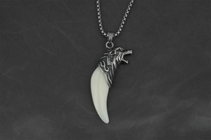 Macro shot of a vintage silver wolf head pendant with white tusk on a steel chain