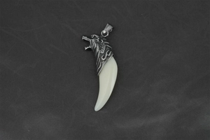Macro view of vintage wolf head tooth pendant with retro silver metal and tribal engraving
