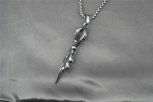 Detailed macro view of retro dragon slayer pestle pendant with embossed textures and square chain