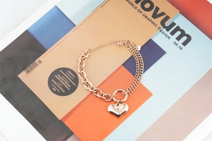 Close-up of rose gold double-strand bracelet with heart pendant on design magazine