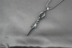 Close-up of retro stainless steel dagger pendant with intricate floral engravings on silk