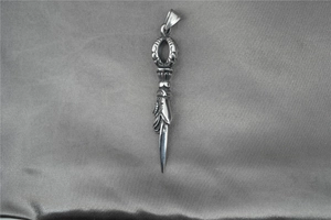 Macro shot of retro Phurba Vajra pendant in distressed titanium steel with ethnic patterns