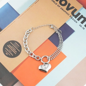 Silver heart pendant bracelet with dual-style chain design on art magazine background