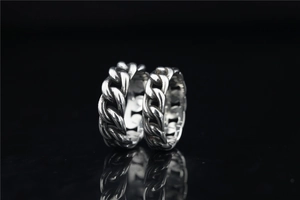 Macro detail of two vintage silver Cuban link chain rings with polished steel texture