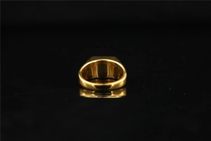 Macro shot of wide gold polished ring with a flat top reflecting on a black surface