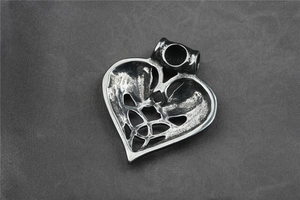 Dettaglio del ciondolo a cuore vintage in argento antico con nodo celtico e teste di lupo
