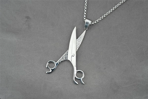 Vue macro du collier pendentif ciseaux avec poignées gravées et chaîne à maillons carrés