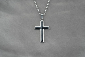 Détail du pendentif croix en argent avec émail noir sur une chaîne en acier inoxydable