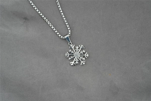 Gros plan détaillé du pendentif flocon de neige évidé sur une chaîne maille vénitienne