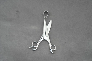 Vue détaillée d'un pendentif ciseaux argenté poli sur fond en tricot gris