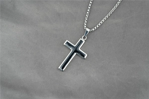 Détail du pendentif croix argentée avec insert noir sur chaîne box en inox