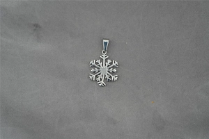 Détail macro d'un pendentif flocon de neige évidé minimaliste en acier inoxydable argenté