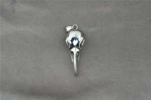 Detailed close-up of a silver polished raven skull pendant on textured grey fabric