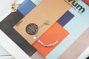 Détail du bracelet en acier titane argenté avec perles et cœurs sur magazine lifestyle