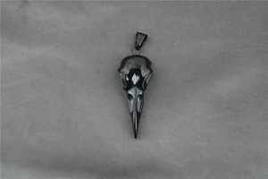Macro detail of a polished black raven skull pendant with gothic punk carving textures