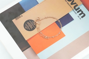 Detail view of double-layered rose gold bracelet with heart charm and delicate beads