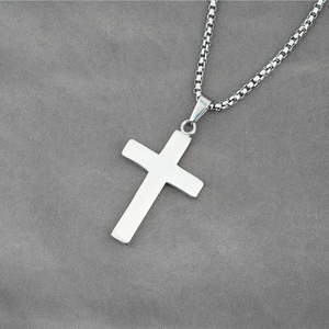 Pendentif croix en acier inoxydable brossé avec chaîne vénitienne sur fond textile gris