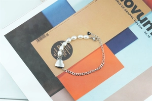 Gros plan détaillé du bracelet en perles et chaîne d'acier avec pendentif en cœur argenté