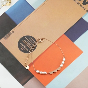 Bracelet en acier inoxydable rose doré avec perles baroques et cœurs sur un magazine