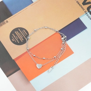 Double-layered titanium steel heart bracelet with beads on a modern magazine background