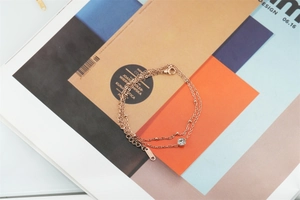 Detail of rose gold double-layered stainless steel bracelet with crystal charm and beads