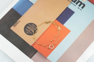 Détail d'un bracelet double couche en titane doré avec pendentif rond serti de cristaux