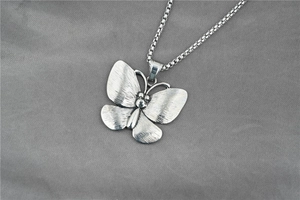 Detail of vintage butterfly pendant in brushed titanium steel with a sleek box chain