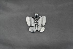 Detailed close-up of a silver butterfly pendant with unique brushed metal texture and bail