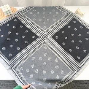 Macro detail of square silk scarf with neutral grey and black floral print pattern