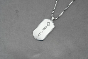 Macro shot of brushed stainless steel dog tag pendant with EXCELON logo on box chain