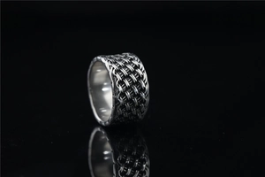 Vue macro d'une bague tressée rétro présentant une finition argentée oxydée et un anneau large