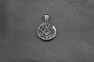 Detail of silver Masonic pendant with G symbol and intricate cutout flame edges