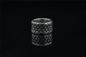 Détail de la texture tressée vintage sur une bague métallique de style industriel gris
