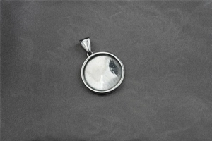 Macro shot of silver titanium steel round pendant with a polished metal surface