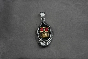 Vue détaillée du pendentif faucheuse avec visage doré et yeux en pierres rouges