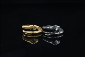 Macro detail of gold and silver snake rings with intricate scale textures on black mirror